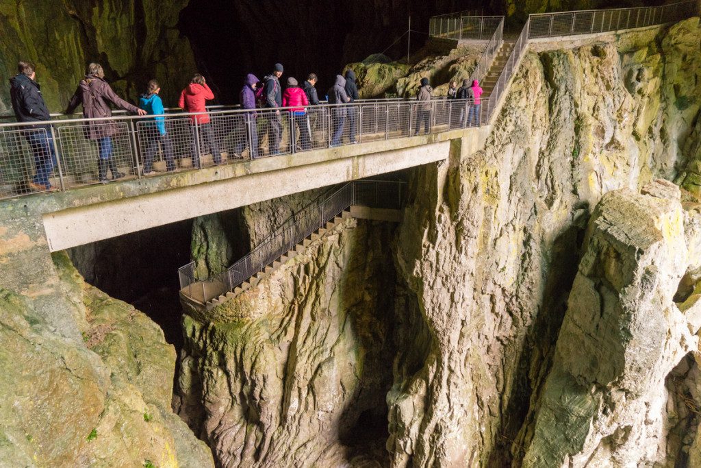 A tour group crosses a bridge just inside the entrance to Mahorcic cave.