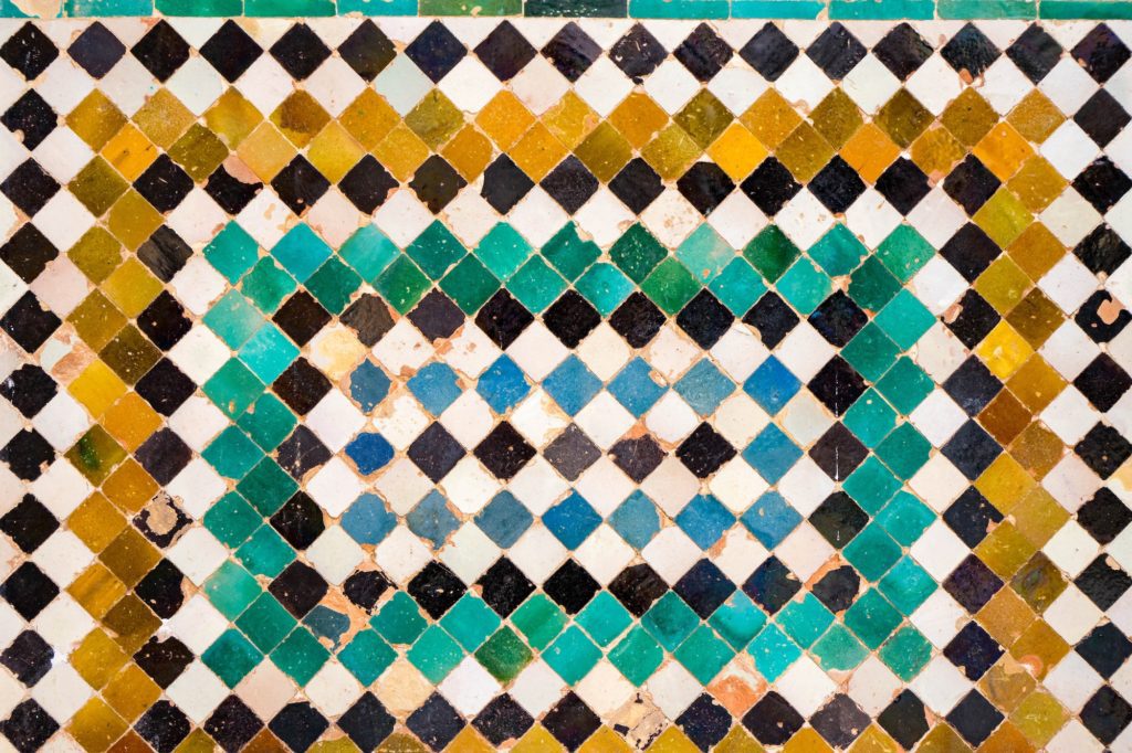 This image displays an intricate mosaic of diamond-shaped tiles in green, white, blue, and brown colors, arranged in a repeating geometric pattern.