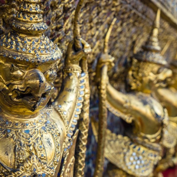 This image shows a row of ornate golden figures with intricate detailing, likely from a Thai temple, reflecting elaborate craftsmanship and cultural heritage.