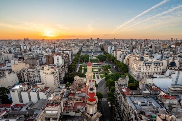 Skyline photo of Buenos Aires Argentina from above the buildings. The sky is a sunset of gold, orange, and blue