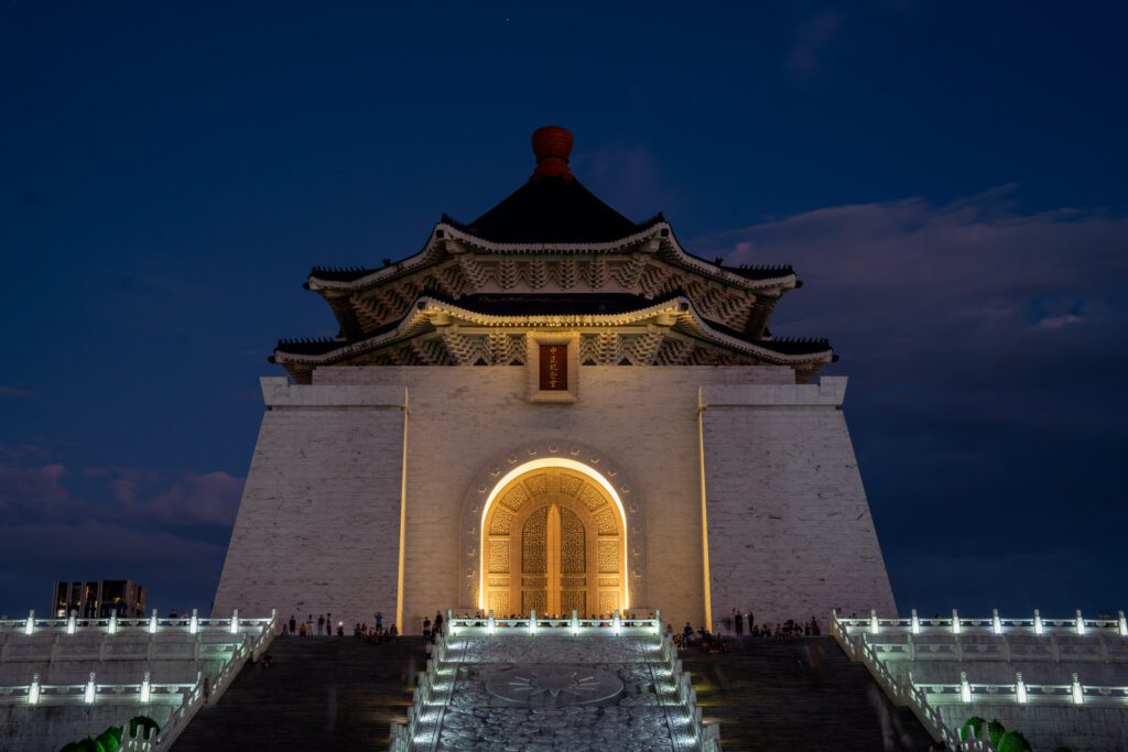 A splendid evening view of the illuminated Chiang Kai-shek Memorial Hall, Taipei, with the grand staircase leading up to the ornate dark-roofed structure.